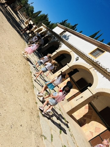 Children sitting along the Andalusian arches at Paradise Stables during a party