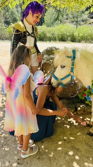 Themed performer helping children meet a unicorn pony