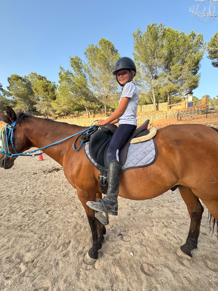 Young rider smiling on a bay horse in the Paradise Stables arena