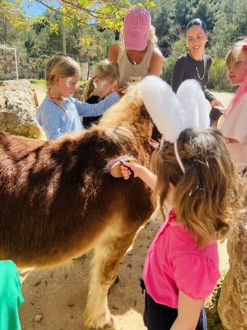 Girls in bunny ears grooming a pony at a Paradise Stables party
