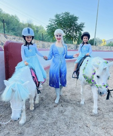 Princess character with two children on unicorn ponies at Paradise Stables