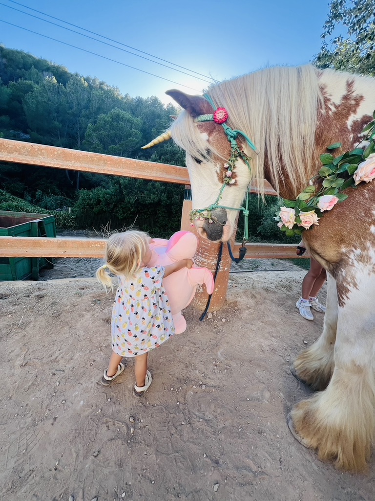 Toddler hugging a decorated unicorn at Paradise Stables